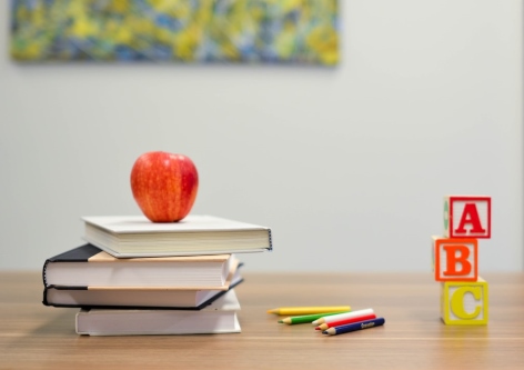 Pile of books, red apple, colouring pencils, ABC blocks 